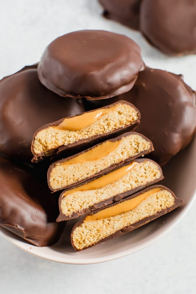 Bowl full of healthy, homemade, vegan and gluten free Tagalong Girl Scout cookies. Cookies are cut in half to you can see the shortbread cookie and b=peanut butter layer, covered in chocolate.