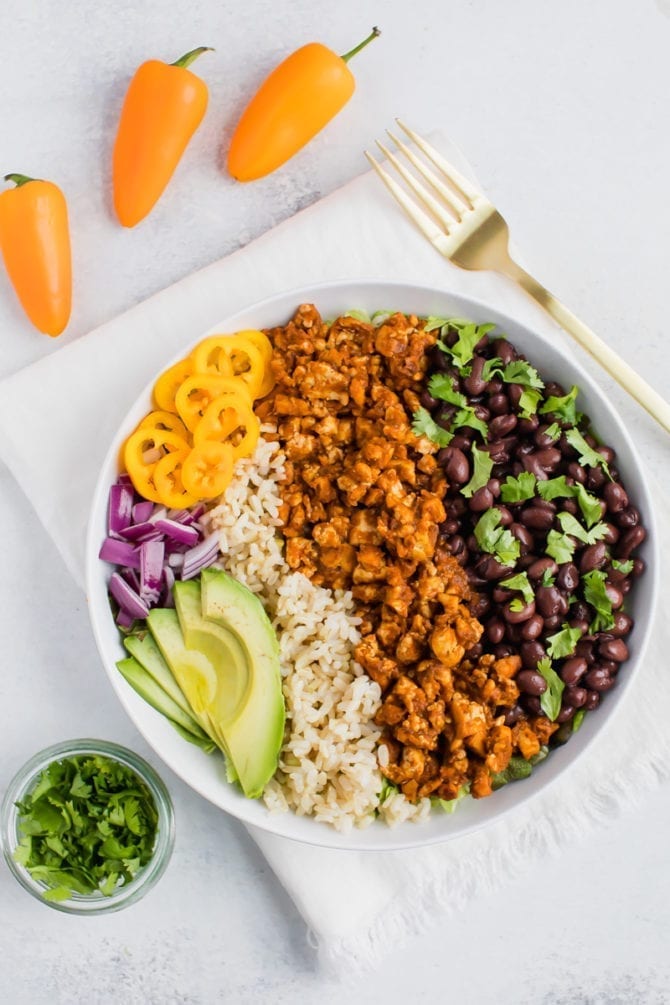 Tofu sofritas burrito bowl with brown rice, black beans, avocado, red onion, yellow bell pepper and cilantro. 