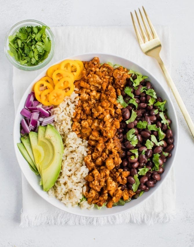 Tofu sofritas burrito bowl with brown rice, black beans, avocado, red onion, yellow bell pepper and cilantro. 