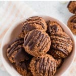 Bowl of chocolate coconut macaroons drizzled with chocolate.