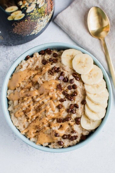 Oatmeal topped with nut butter drizzle, chocolate chips, and sliced banana. Spoon on the side.