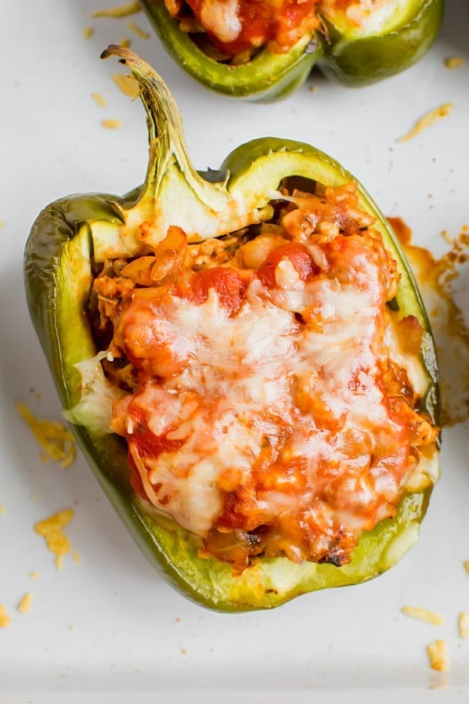 Turkey stuffed pepper in a baking dish. Peppers stuffed with turkey, rice, onions and tomato sauce, topped with cheese.