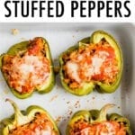 Four stuffed peppers in a baking dish. Peppers stuffed with turkey, rice, onions and tomato sauce, topped with cheese.