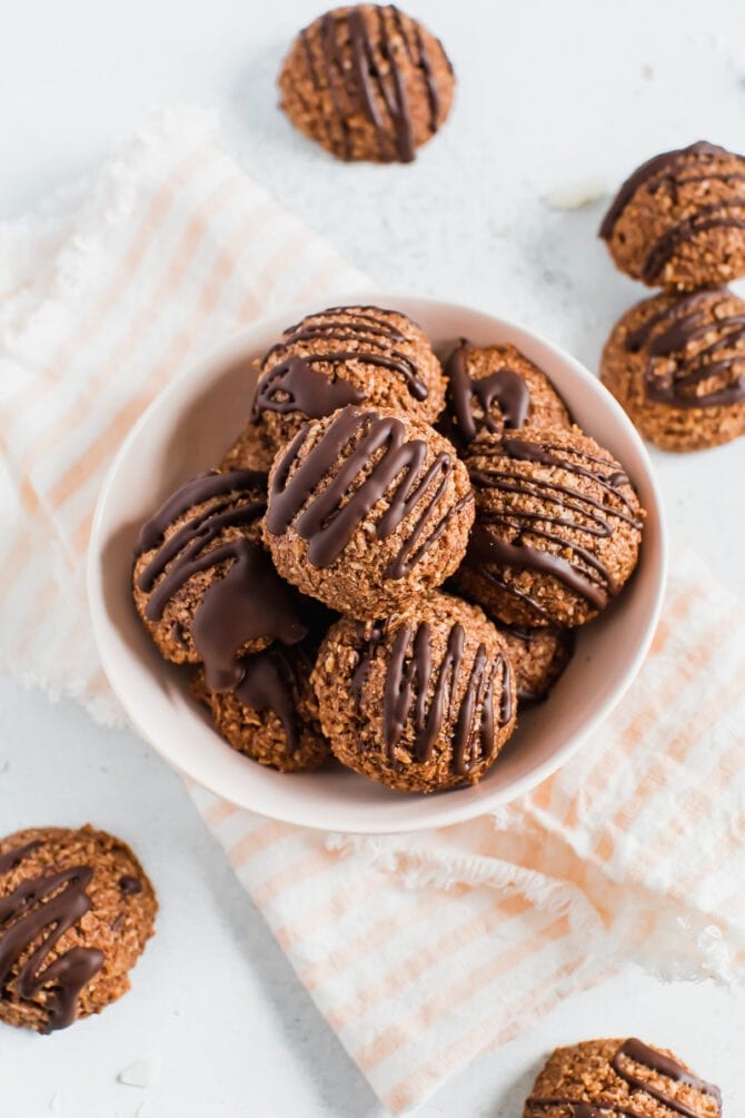 Bowl of chocolate coconut macaroons drizzled with chocolate.