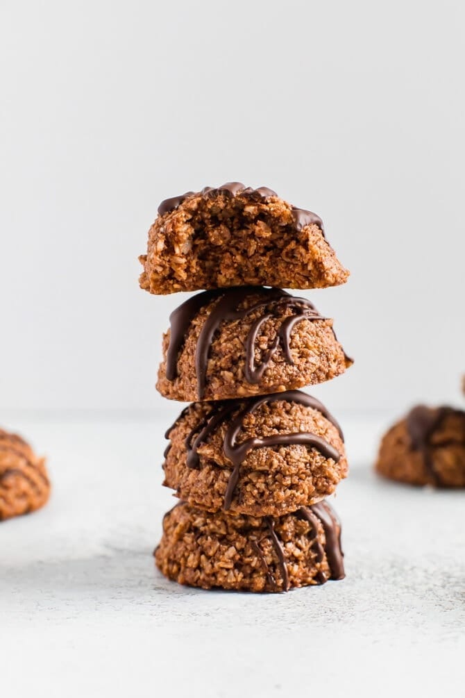 Stack of four vegan and gluten-free chocolate coconut macaroons drizzled with chocolate.