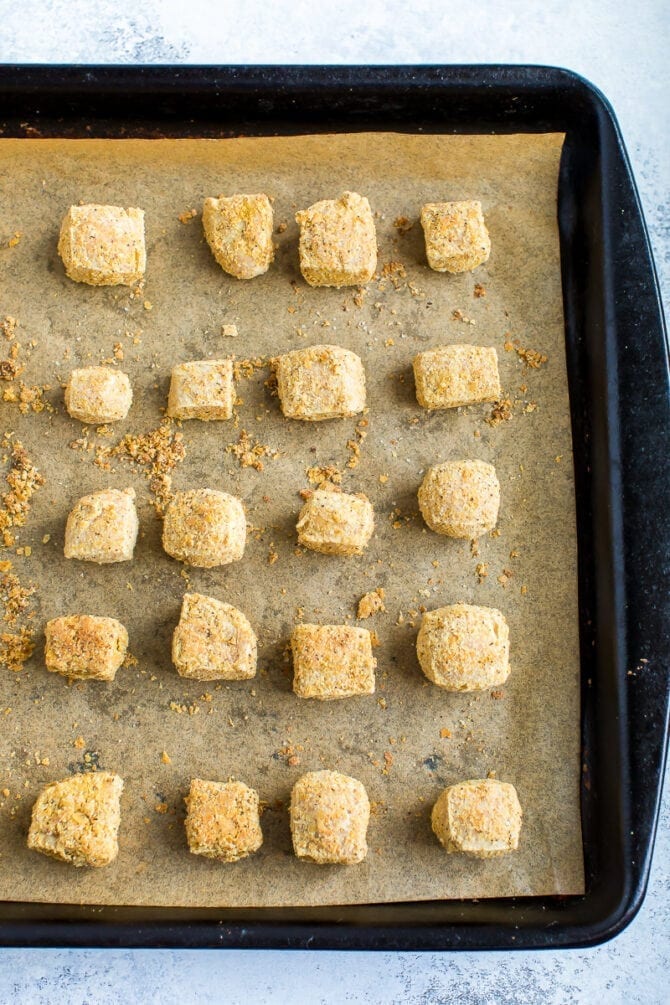 Cubes of crispy baked tofu on a baking sheet lined with parchment paper.