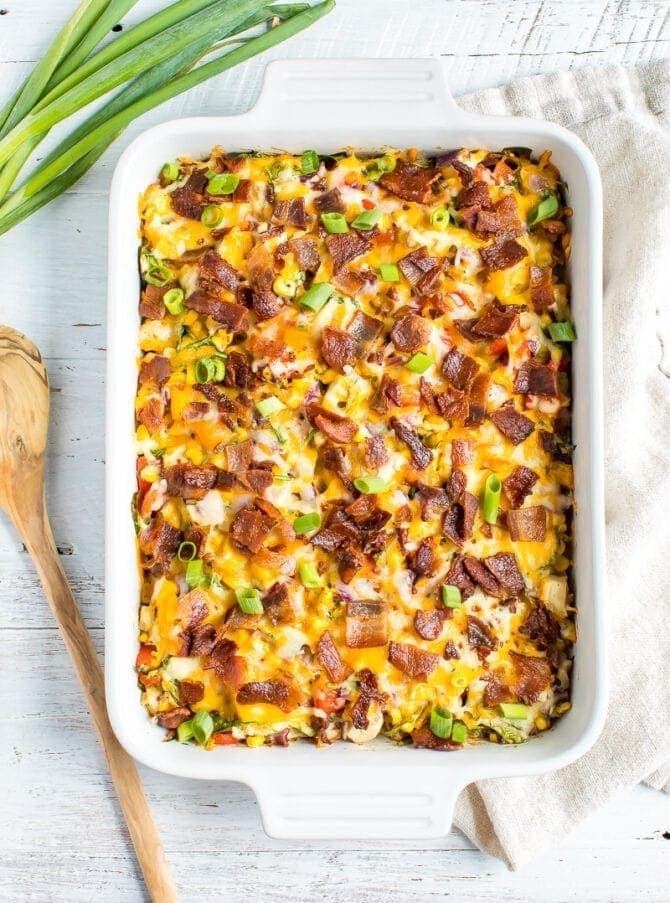 chicken casserole in a casserole dish topped with cheese, bacon, and green onions.