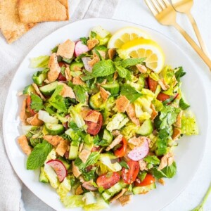 Plate of fattoush salad made with lettuce, herbs, tomato, cucumber, radishes and crumbled pita chips.