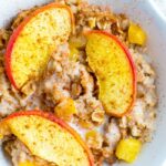 Bowl of peach baked oatmeal, topped with almond milk and cinnamon.