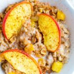 Bowl of peach baked oatmeal, topped with almond milk and cinnamon.