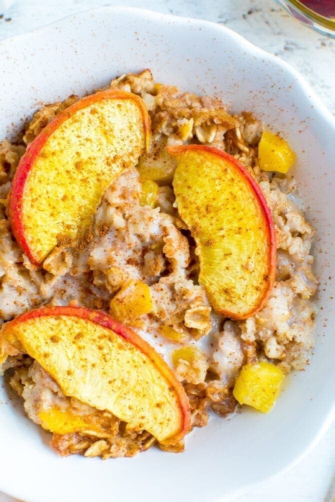 Bowl of peach baked oatmeal, topped with almond milk and cinnamon.