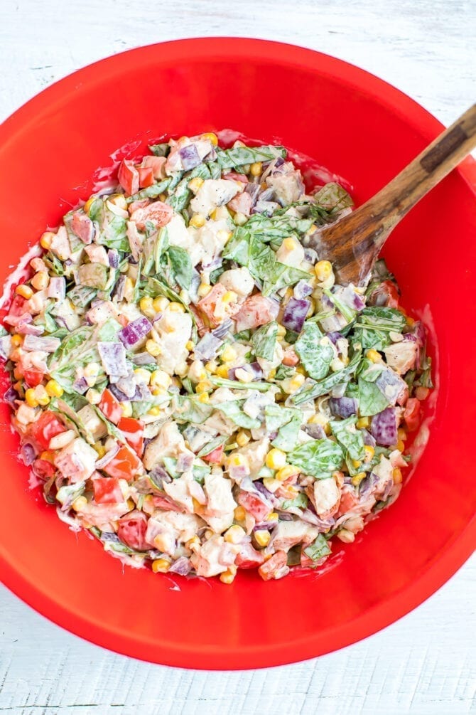 confetti chicken casserole ingredients mixed in a bowl: kale, corn, chicken, onion, peppers and mayo.