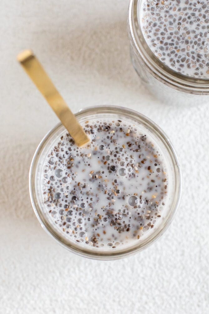 A mason jar with chia seeds just after being stirred together with a spoon for chia pudding. 