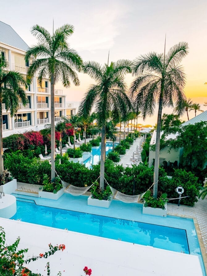 View from a hotel room at a Grand Cayman resort. Views of the pools, palm trees, and ocean.