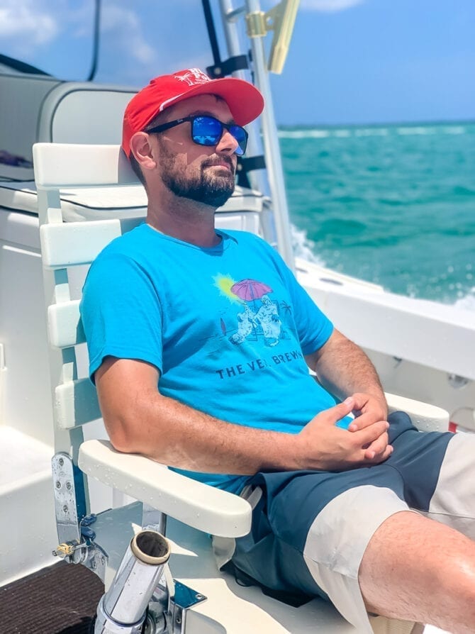 Man wearing sunglasses and a baseball cap sitting on a boat in the Caribbean. 