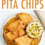 Baked pita chips on a plate with a bowl of hummus.