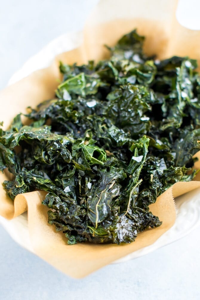 Bowl lined with parchment paper and filled with kale chips