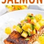 Blacked salmon topped with pineapple salsa and sitting on top of a plate of rice.