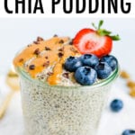 Jar of peanut butter chia seed pudding topped with cacao nibs, blueberries, and a strawberry.