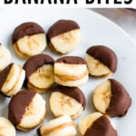 Chocolate peanut butter banana bites on a plate. Slices of banana sandwiched with peanut butter and dipped half in chocolate and frozen.