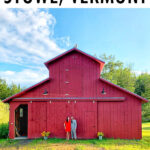 Couple standing in front of a red barn.