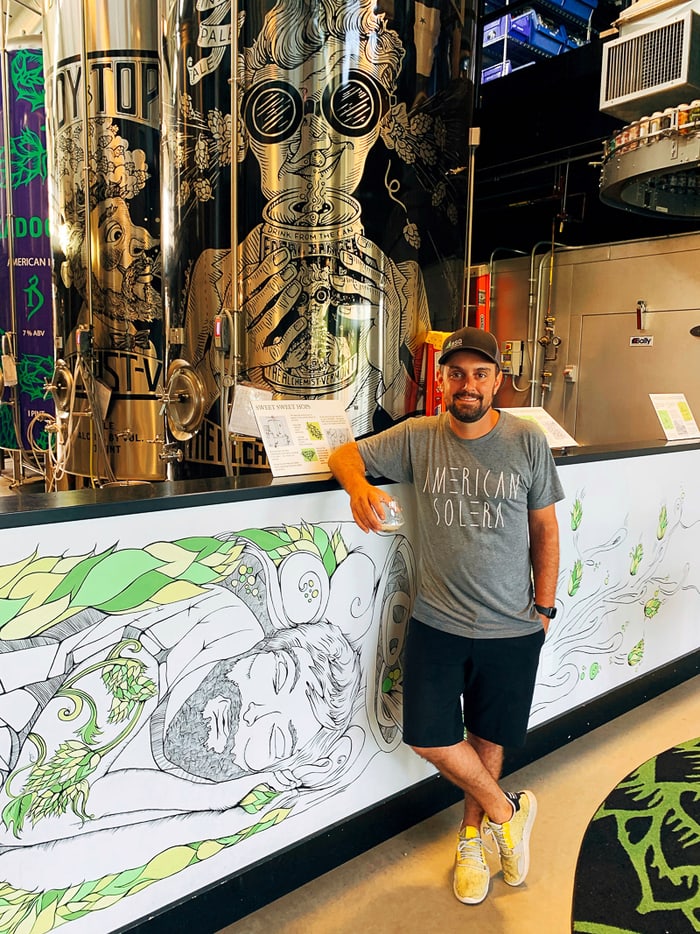 Man standing in front of a brewing room in a Vermont brewery.