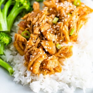 Plate with broccoli, rice, and shredded teriyaki chicken topped with green onions.