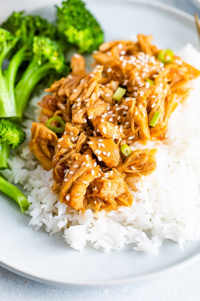 Plate with broccoli, rice, and shredded teriyaki chicken topped with green onions.
