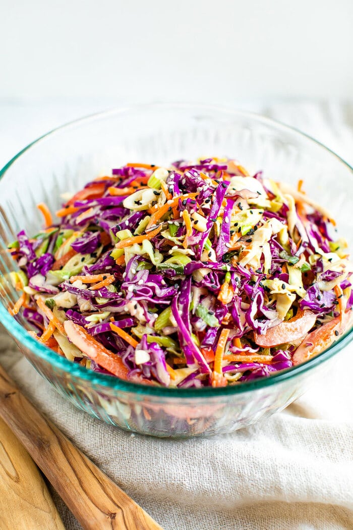 Bowl of asian slaw made with purple cabbage, scallions, peppers and carrots.