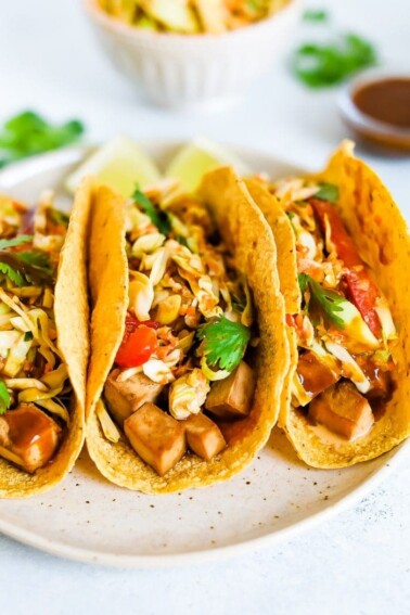 Three asian tofu tacos with baked teriyaki tofu, asian slaw, and cilantro.