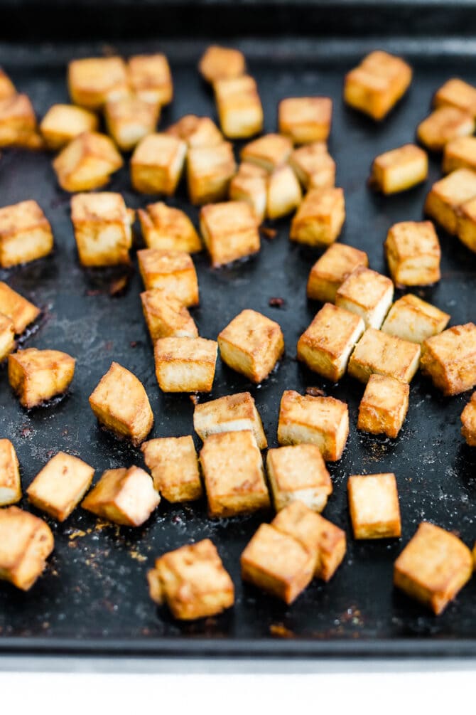 Crispy tofu baking on a cooking sheet.