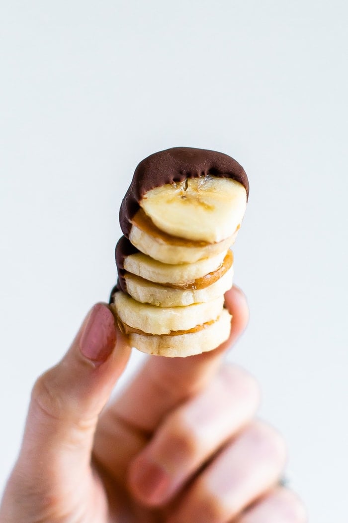 Hand holding a stack of frozen peanut butter banana bites.