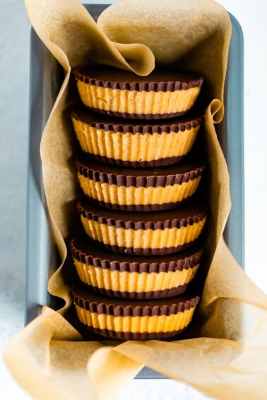 Stack of homemade peanut butter cups in parchment paper, in a bundt pan.