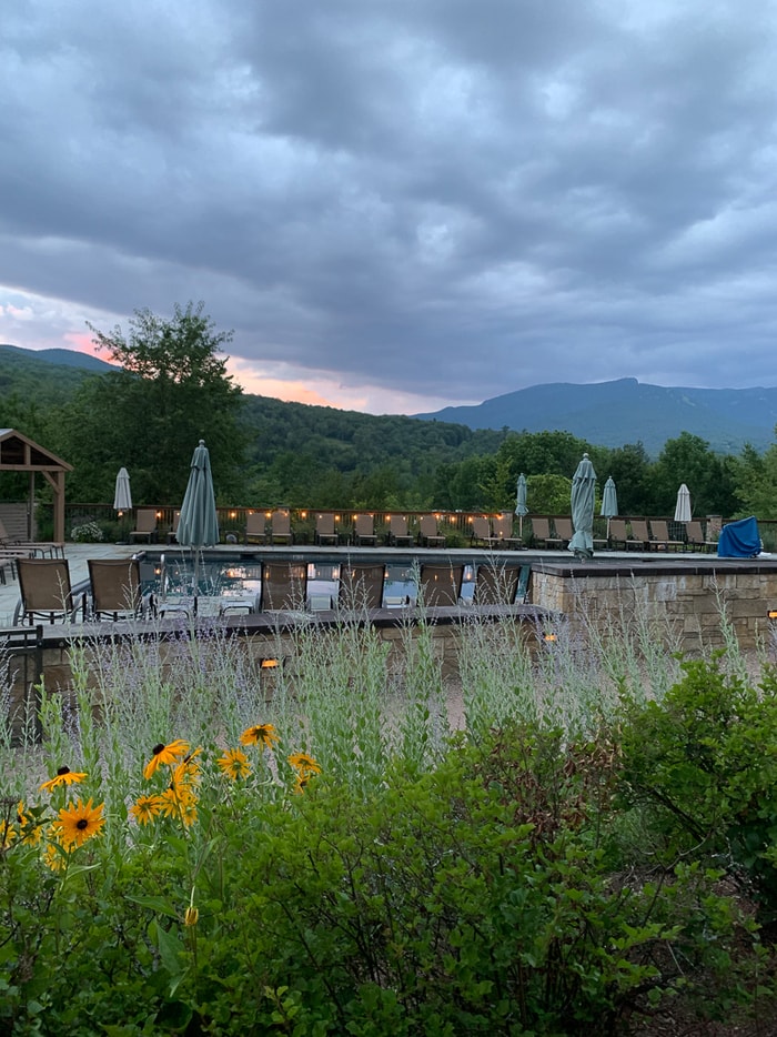 View of a resort pool in Stowe, Vermont. The pool has a wild flower garden and a view of the mountains.