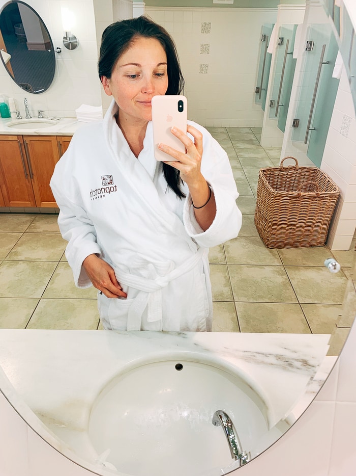 Woman taking a mirror selfie wearing a spa robe.