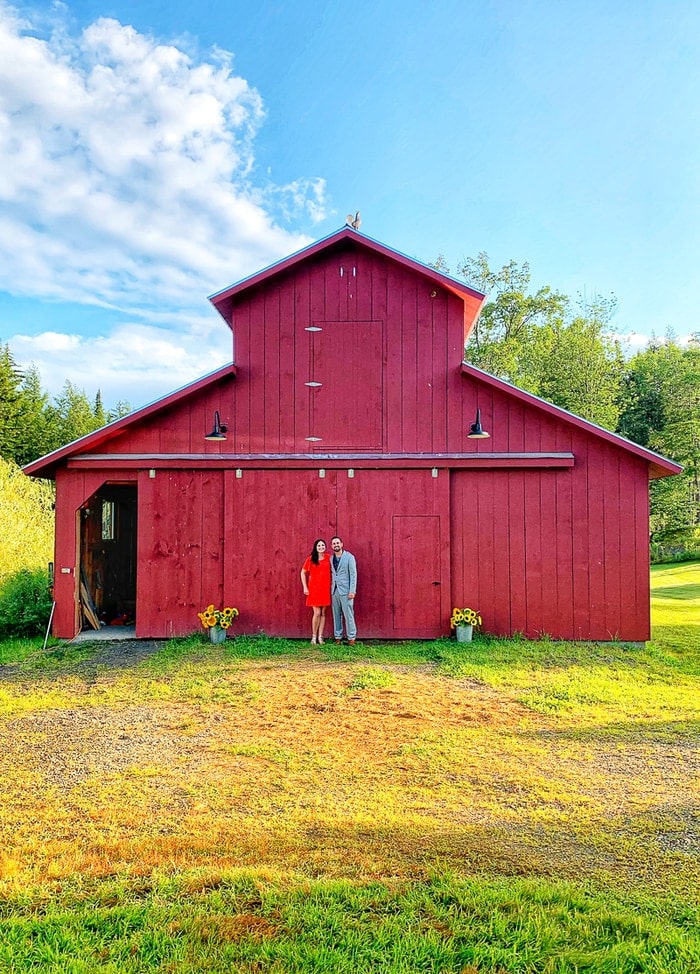 Couple standing in front of a red barn.