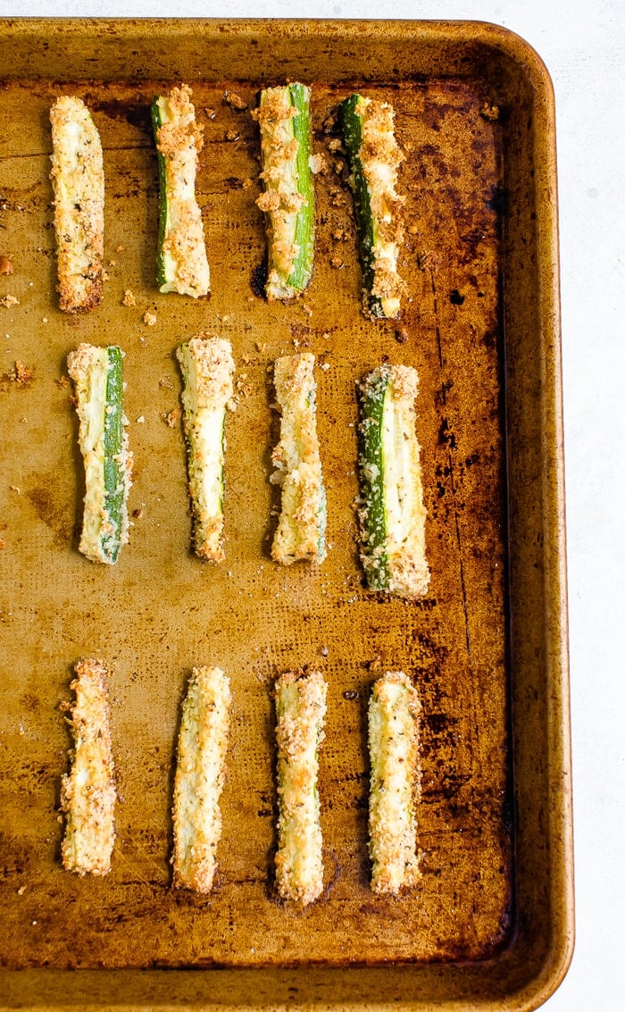 Sheet pan with crispy baked zucchini fries lined up on the sheet.