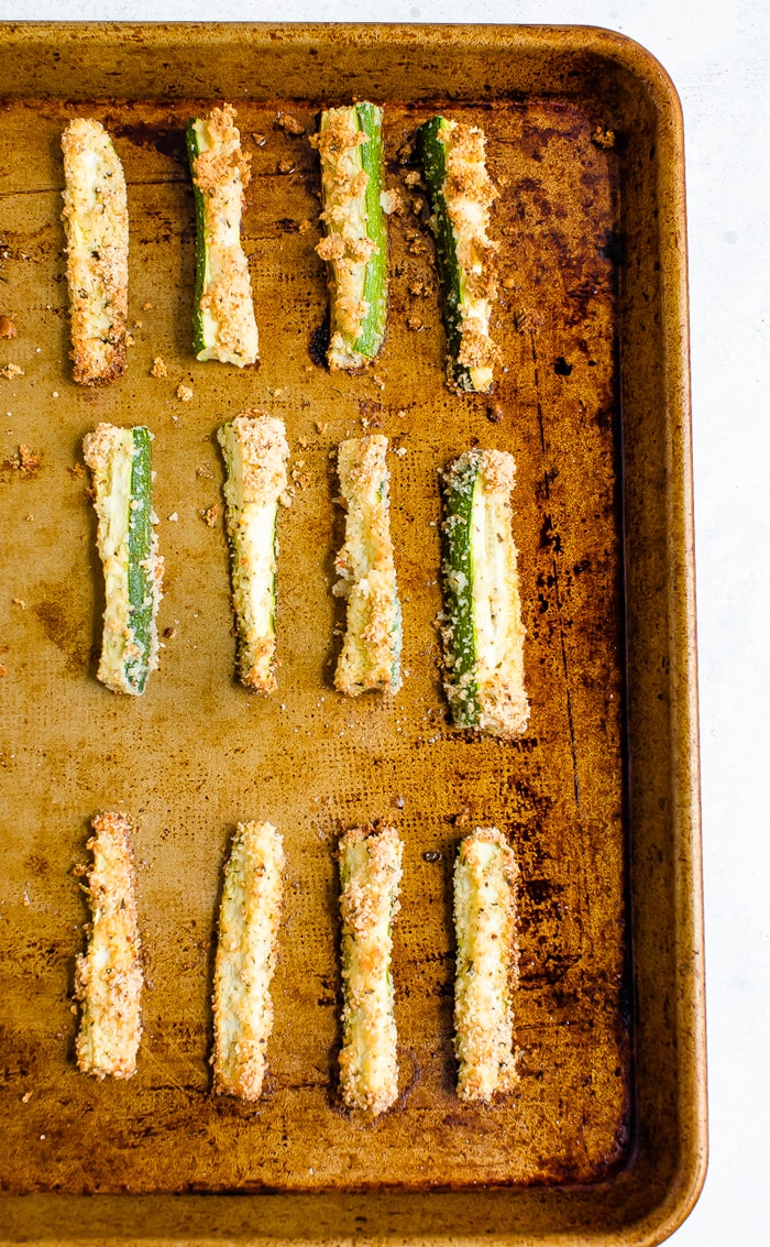 Sheet pan with crispy baked zucchini fries lined up on the sheet.