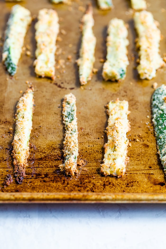 Sheet pan with crispy baked zucchini fries lined up on the sheet.
