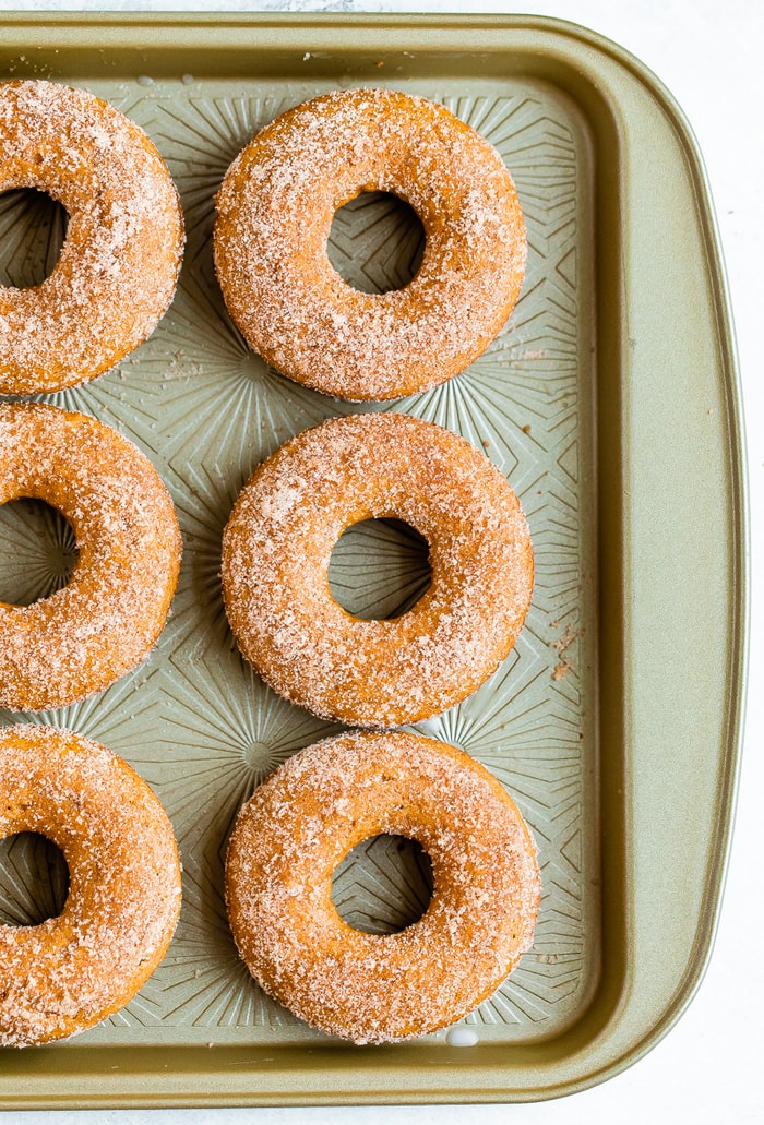 Cookie sheet with baked apple cider donuts on it.