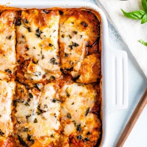 A baking dish with eggplant parmesan and cut into pieces.