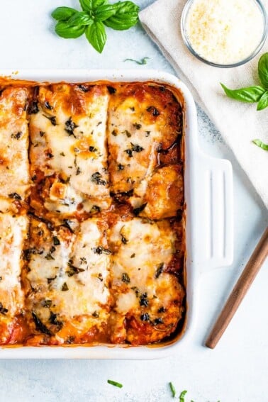 A baking dish with eggplant parmesan and cut into pieces.