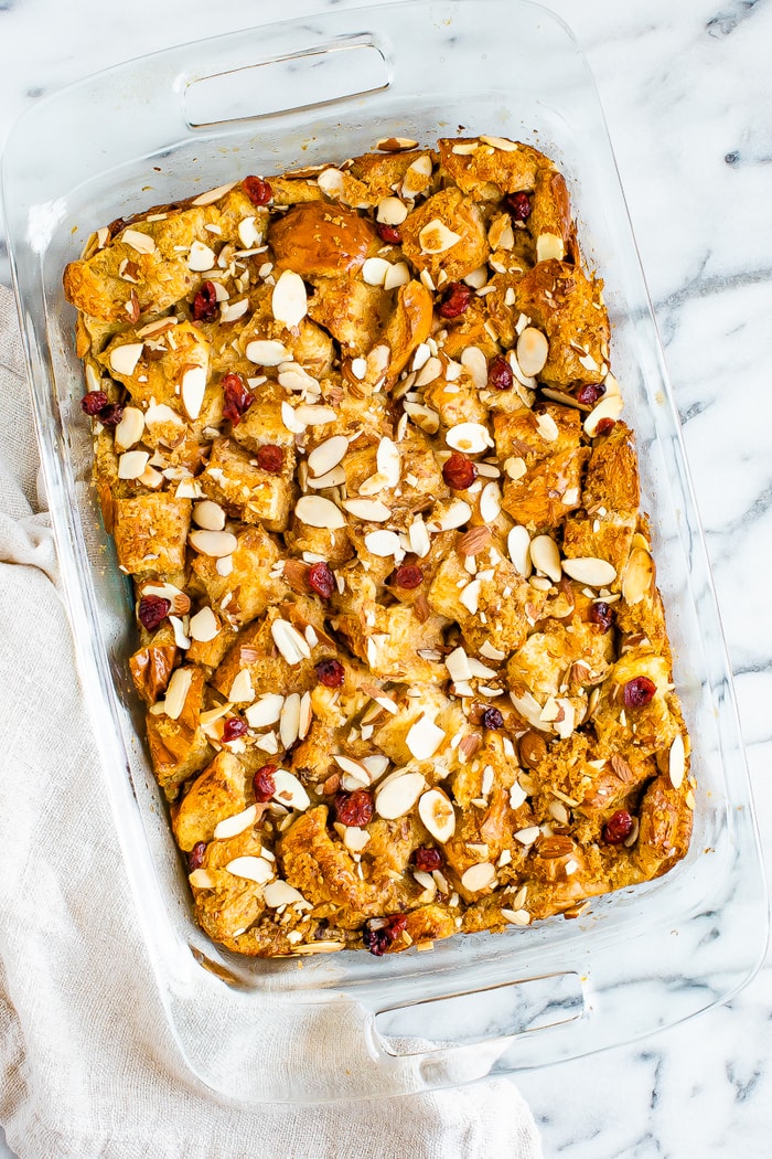 Casserole dish of a french toast bake toped with cranberries and slivered almonds.