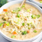 Bowl of broccoli cheddar soup with a gold spoon in the bowl.