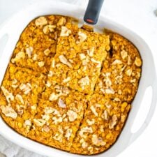 A spatula is lifting a slice of pumpkin baked oatmeal out of a baking dish.