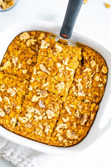 A spatula is lifting a slice of pumpkin baked oatmeal out of a baking dish.