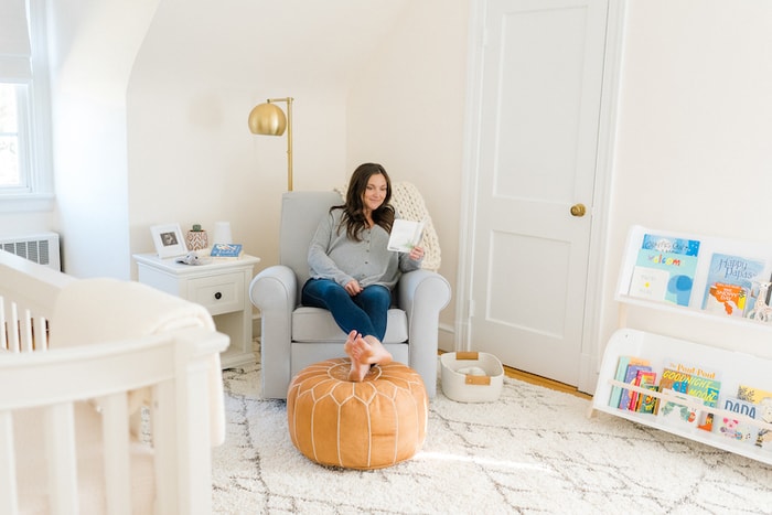 Expecting mom in glider in nursery reading a book. 