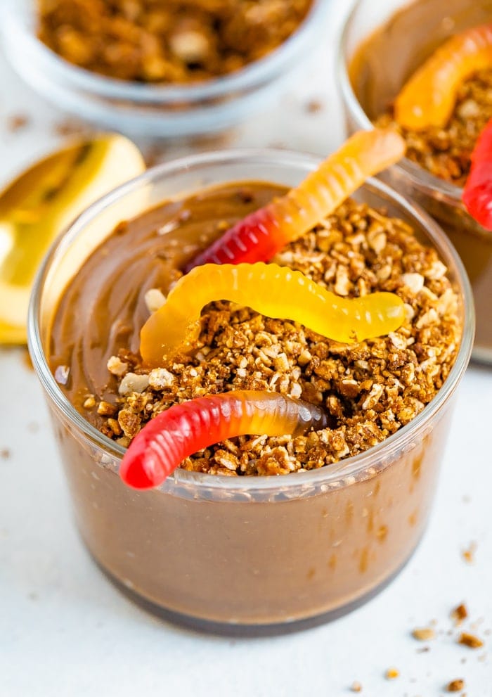 Dirt cup with chocolate avocado pudding topped with granola and gummy worms.