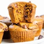 Two healthy pumpkin muffins stacked with a bite taken out of the top muffin.