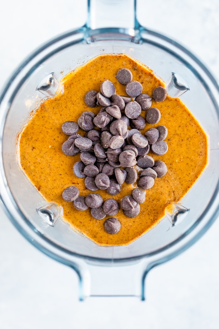 Overhead shot of a blender with flourless pumpkin batter and chocolate chips on top.